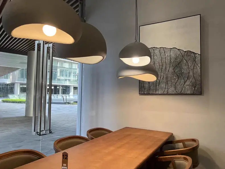 Modern dining room featuring Nordic minimalist pendant lights above a wooden table with stylish chairs.